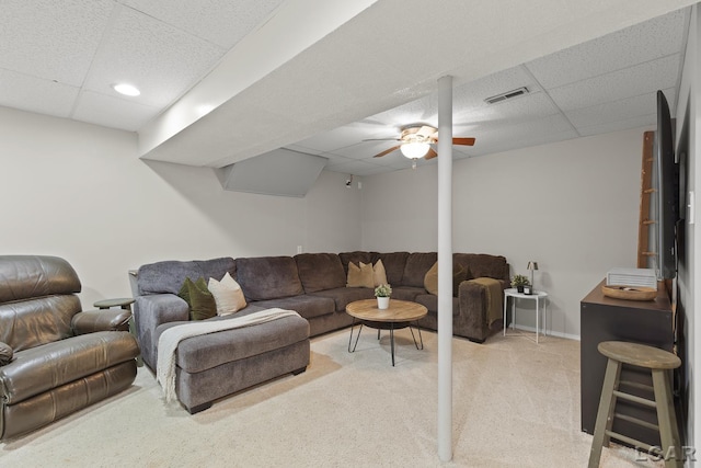 living area featuring a drop ceiling, light carpet, and ceiling fan