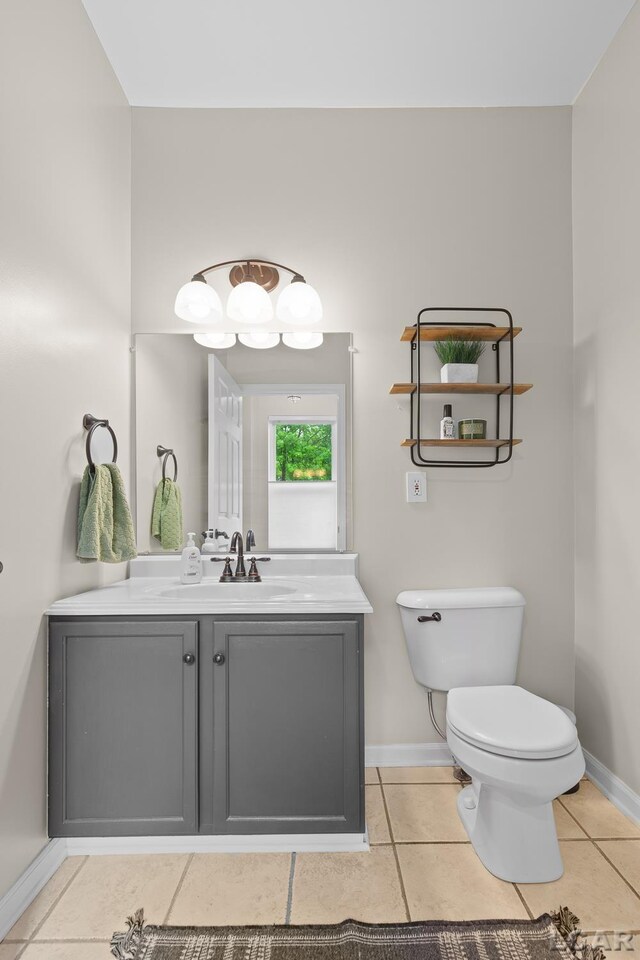 half bath featuring toilet, baseboards, tile patterned floors, and vanity