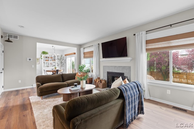 living room with healthy amount of natural light, baseboards, light wood-style flooring, and a fireplace