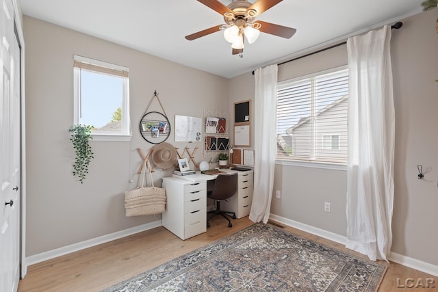 home office with a ceiling fan, light wood finished floors, and baseboards