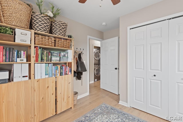 interior space with stacked washer and clothes dryer, wood finished floors, a closet, baseboards, and a ceiling fan