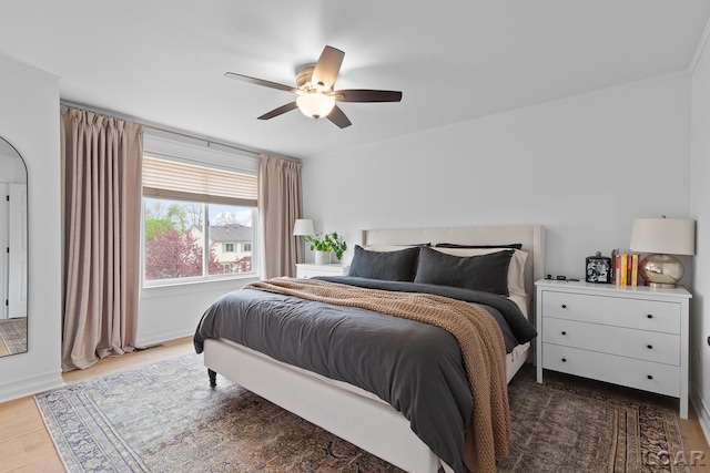 bedroom with wood finished floors, ceiling fan, and ornamental molding