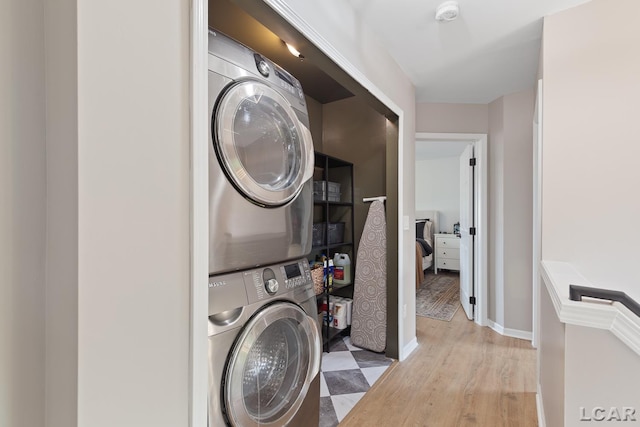 washroom with stacked washer / dryer, light wood-style floors, and baseboards