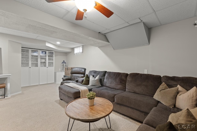 living area with a paneled ceiling, carpet, and a ceiling fan