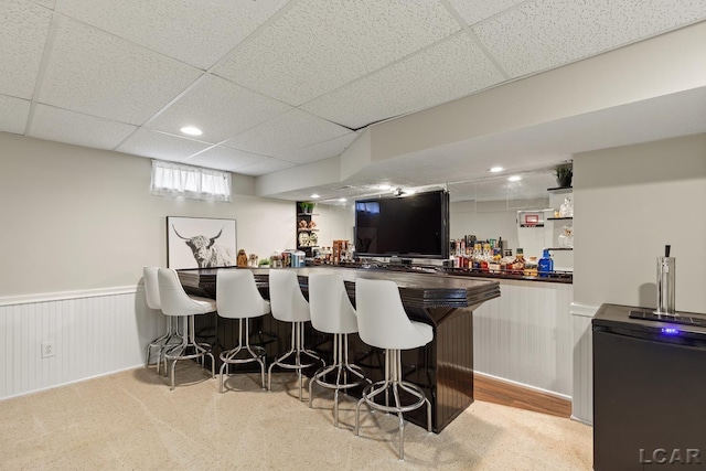 indoor dry bar featuring a paneled ceiling, wainscoting, recessed lighting, and fridge