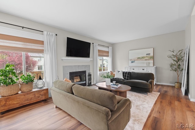 living area featuring wood finished floors, a glass covered fireplace, and baseboards