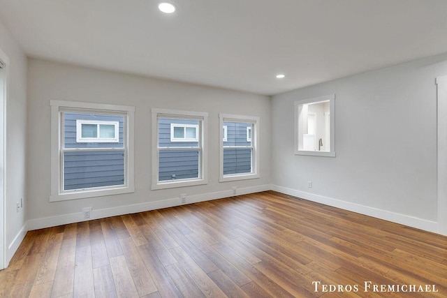 spare room featuring baseboards, wood-type flooring, and recessed lighting