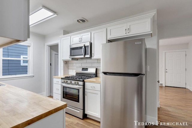 kitchen featuring appliances with stainless steel finishes, wooden counters, light wood-style floors, and white cabinets