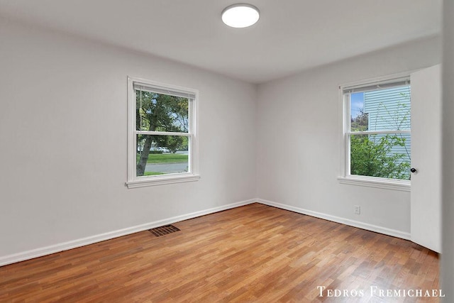 unfurnished room featuring plenty of natural light, wood finished floors, and baseboards