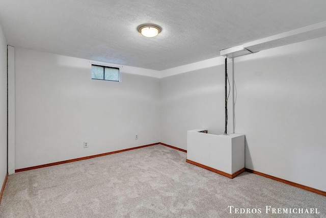 basement featuring a textured ceiling, carpet, and baseboards