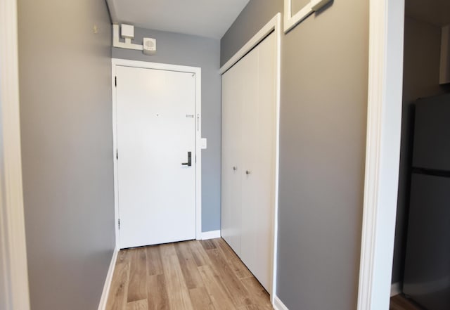 corridor with light wood-style floors and baseboards