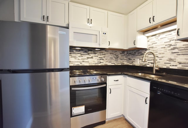 kitchen with appliances with stainless steel finishes, a sink, decorative backsplash, and white cabinets