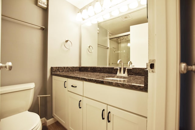 bathroom featuring toilet, a shower with door, and vanity