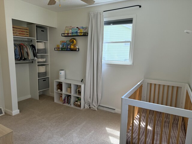 1335 N Sherman Rd, Ludington, MI 49431 - bedroom featuring a crib, carpet flooring, a baseboard heating unit, a closet, and baseboards