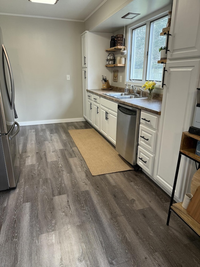 1335 N Sherman Rd, Ludington, MI 49431 - kitchen featuring appliances with stainless steel finishes, a sink, dark wood-style floors, ornamental molding, and white cabinetry