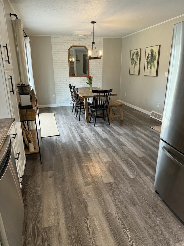 1335 N Sherman Rd, Ludington, MI 49431 - dining area with dark wood finished floors, baseboards, a textured ceiling, brick wall, and a chandelier