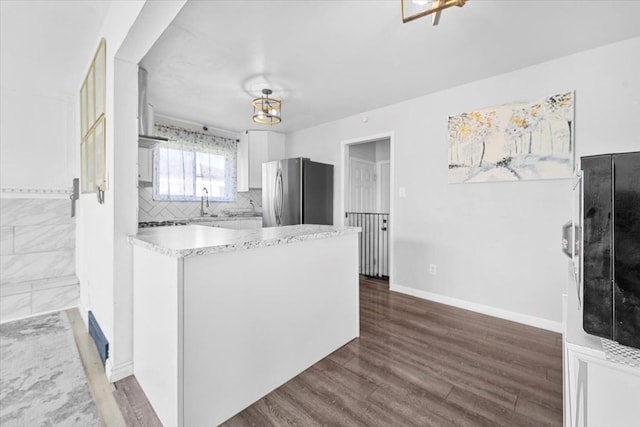 kitchen featuring freestanding refrigerator, light countertops, white cabinets, dark wood-style flooring, and a peninsula