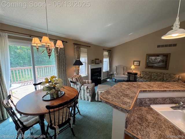 4522 Willow View Ct, Howell, MI 48843 - dining room featuring carpet floors, lofted ceiling, a chandelier, a textured ceiling, and a glass covered fireplace