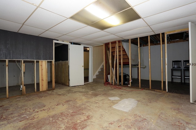 unfinished below grade area with stairs and a paneled ceiling
