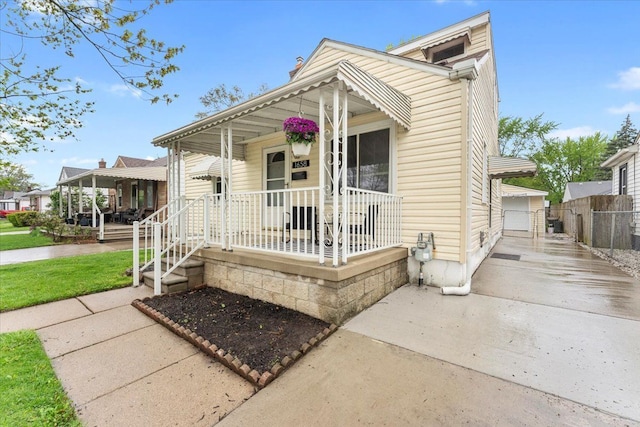 shotgun-style home featuring a porch, fence, and a gate