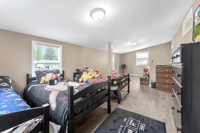 bedroom featuring light wood-style flooring, lofted ceiling, and baseboards