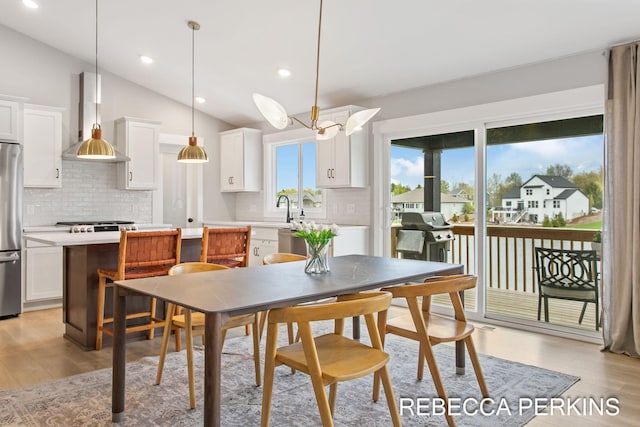 dining room featuring vaulted ceiling, light wood-style floors, and recessed lighting