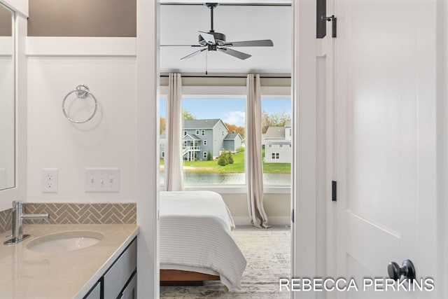 bathroom with vanity, backsplash, a ceiling fan, and a water view