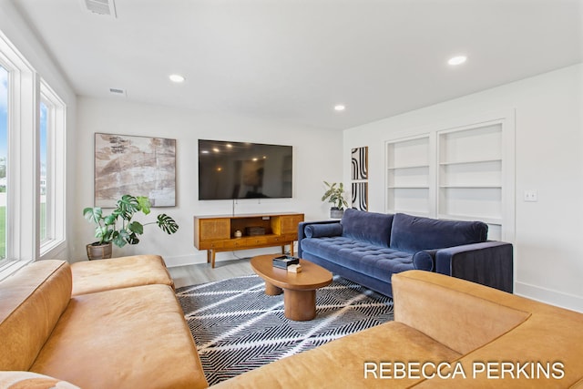 living area featuring baseboards, recessed lighting, wood finished floors, and built in features