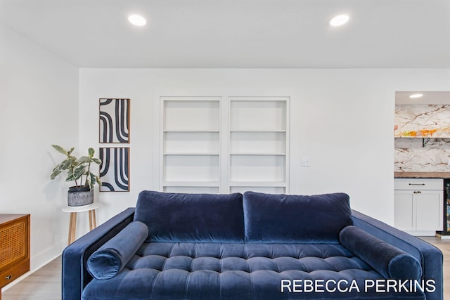 living room with light wood finished floors, built in features, and recessed lighting