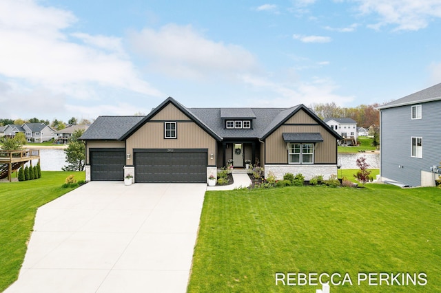 view of front facade featuring a front yard, driveway, a garage, a water view, and brick siding
