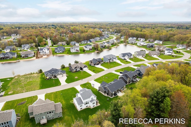 aerial view of residential area with a large body of water and a heavily wooded area