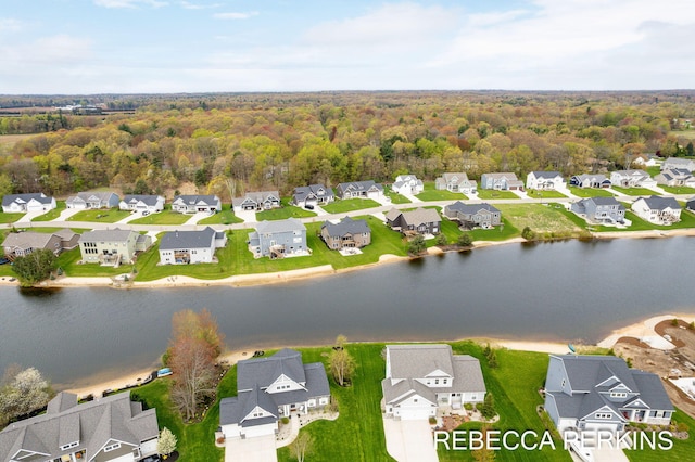aerial view of residential area with a nearby body of water and a heavily wooded area