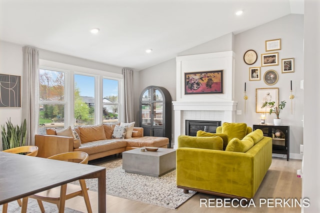 living room featuring lofted ceiling, light wood-style flooring, a fireplace, and recessed lighting