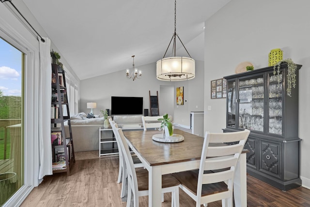 dining area with a chandelier, wood finished floors, high vaulted ceiling, and baseboards