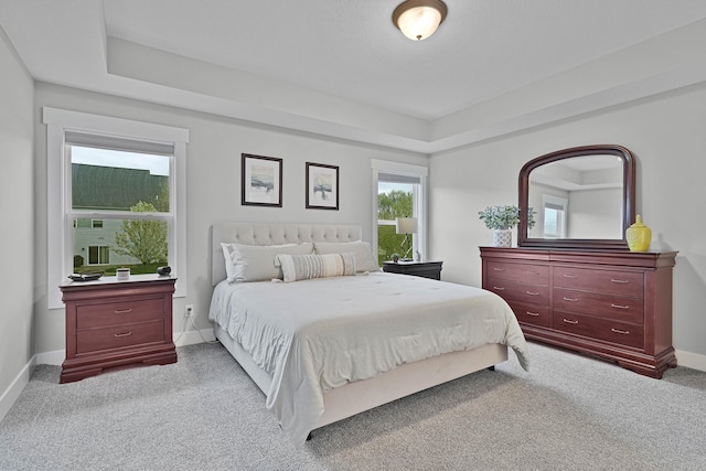 carpeted bedroom with baseboards and a tray ceiling
