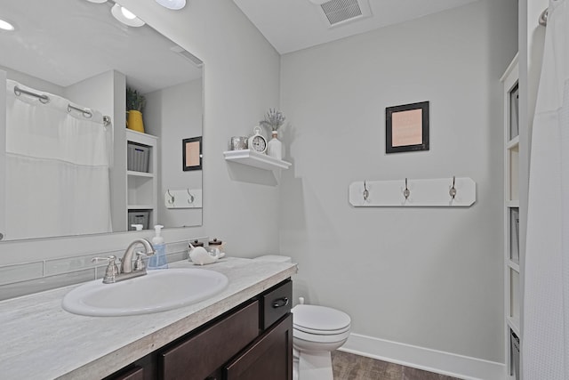 full bath featuring toilet, wood finished floors, vanity, and baseboards