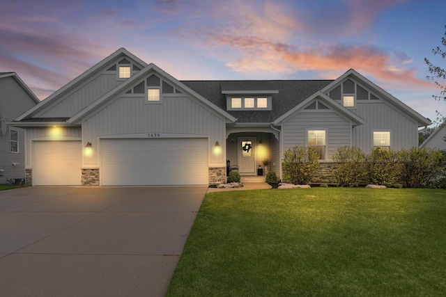 craftsman house featuring board and batten siding, stone siding, a garage, and a front lawn