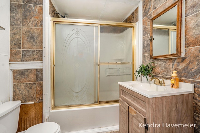 747 Alpine Ave NW, Grand Rapids, MI 49504 - full bath with toilet, shower / bath combination with glass door, vanity, and tile walls