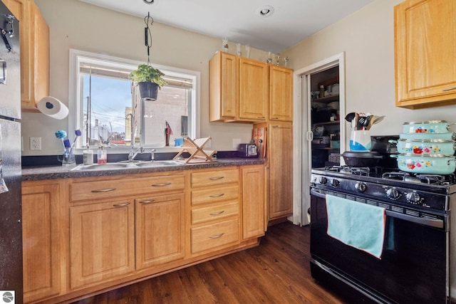 110 W 4th St, Kalkaska, MI 49646 - kitchen with gas stove, a sink, dark wood-type flooring, dark countertops, and light brown cabinetry