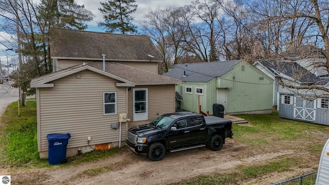 110 W 4th St, Kalkaska, MI 49646 - view of side of property featuring a shingled roof, an outbuilding, and a storage shed