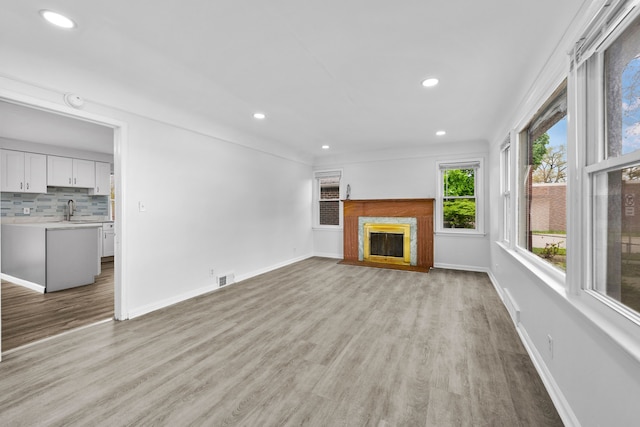 839 E Hayes Ave, Hazel Park, MI 48030 - unfurnished living room with a sink, light wood finished floors, recessed lighting, a high end fireplace, and baseboards
