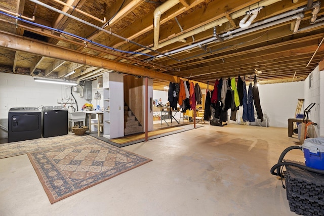 unfinished basement featuring washing machine and clothes dryer, stairway, and concrete block wall