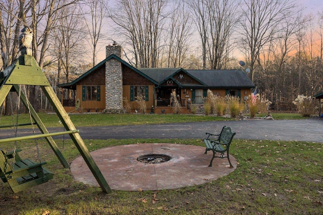 view of front of home featuring a fire pit, a chimney, and a lawn