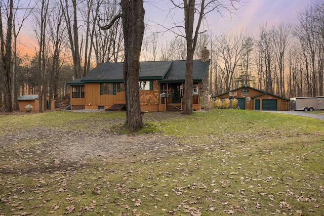 view of front of property featuring a chimney, an outbuilding, a lawn, and covered porch