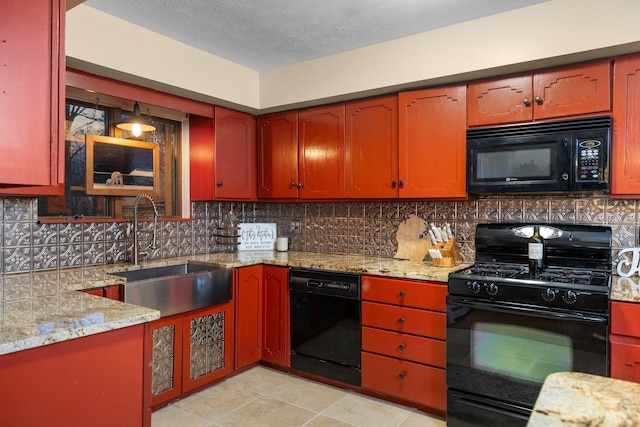 kitchen featuring black appliances, a sink, tasteful backsplash, light stone counters, and light tile patterned floors