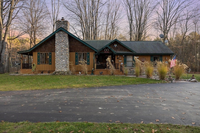 view of front of home with a porch, a chimney, and a front lawn