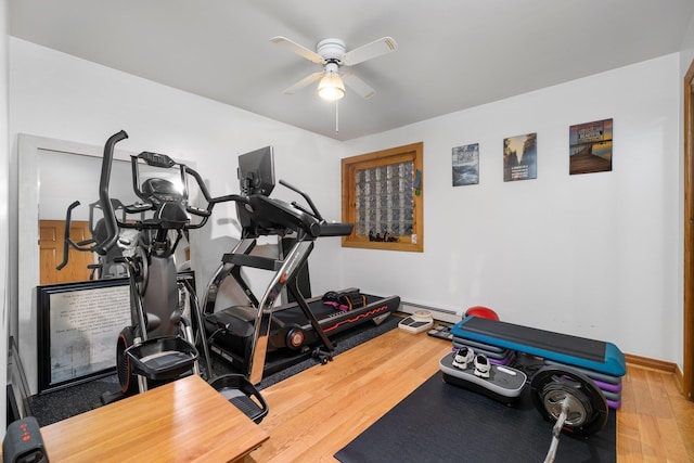 exercise room with ceiling fan, wood finished floors, baseboard heating, and baseboards