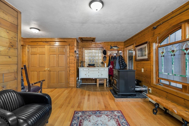 living area with a wood stove, wood walls, hardwood / wood-style floors, plenty of natural light, and a textured ceiling