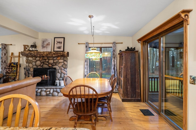 dining area with light wood finished floors, a fireplace, and vaulted ceiling