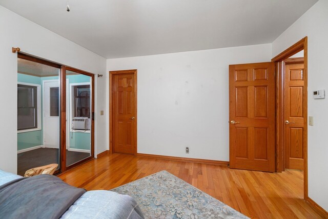 bedroom featuring light wood-type flooring, baseboards, and cooling unit
